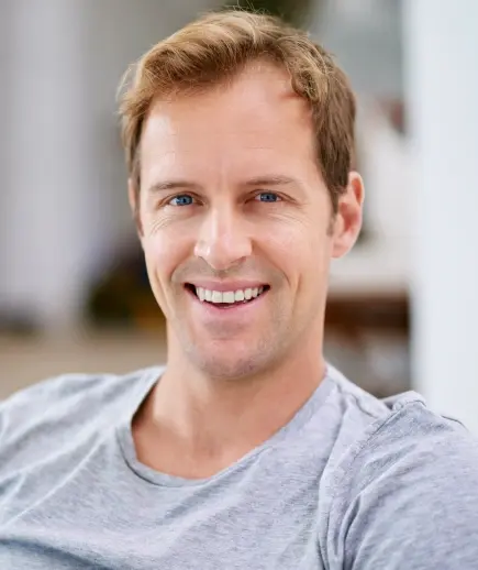 Smiling man in gray shirt representing sedation dentistry patient care at Beverly Hills dental practice.